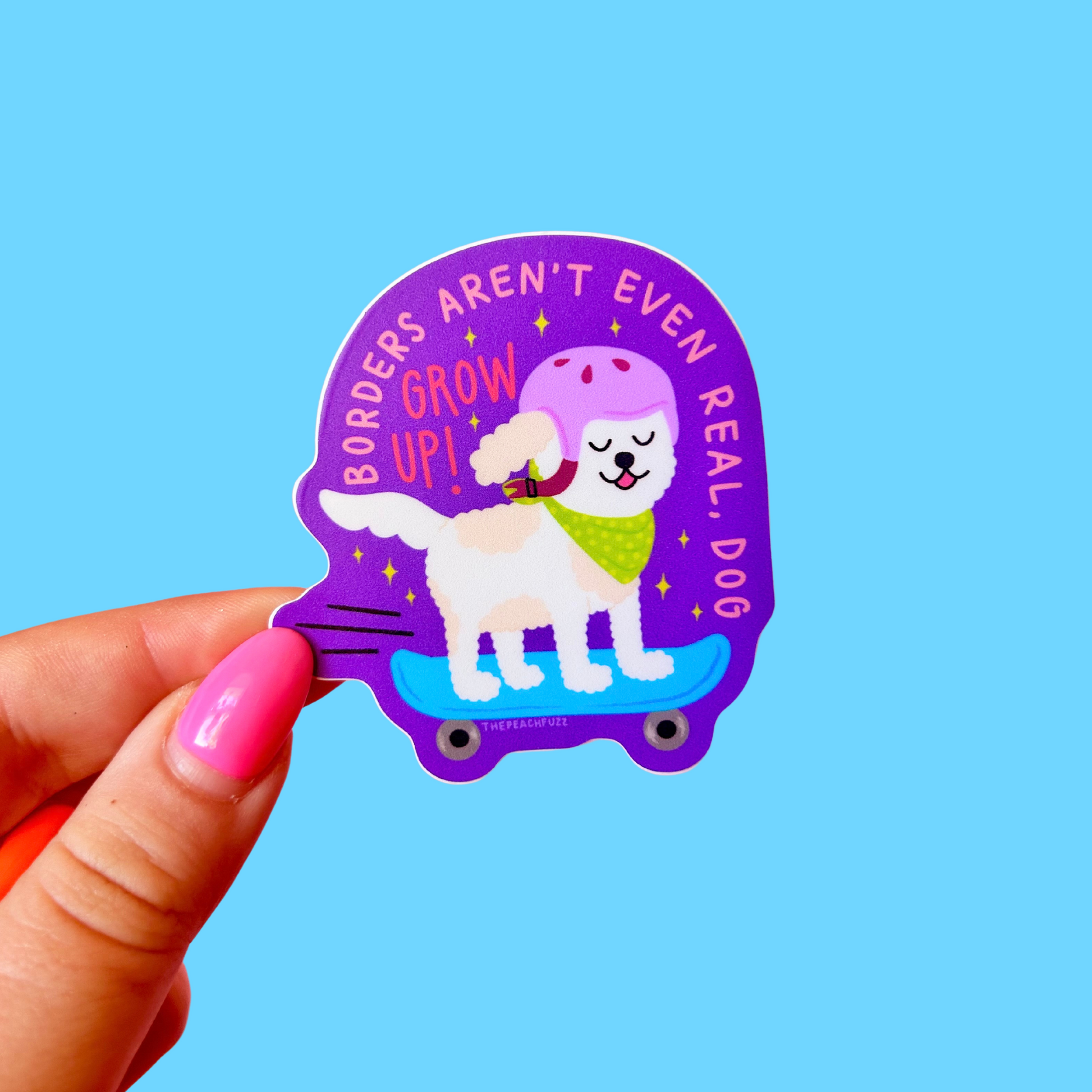 Sticker with a dog on a skateboard and text held by a hand against a blue background